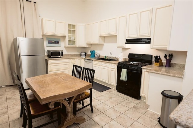 152729 Dumaine St, New Orleans, LA 70116 - kitchen with appliances with stainless steel finishes, light tile patterned flooring, under cabinet range hood, and glass insert cabinets