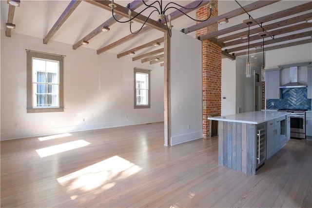 623-25 Louisa St, New Orleans, LA 70117 - kitchen featuring stainless steel range oven, wall chimney range hood, beamed ceiling, beverage cooler, and wood finished floors