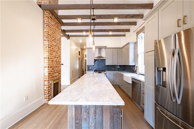 623-25 Louisa St, New Orleans, LA 70117 - kitchen with stainless steel appliances, wall chimney range hood, a kitchen island, light wood finished floors, and beamed ceiling