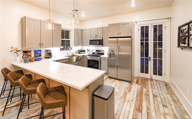 623-25 Louisa St, New Orleans, LA 70117 - kitchen featuring stainless steel appliances, a peninsula, a breakfast bar area, gray cabinets, and hanging light fixtures