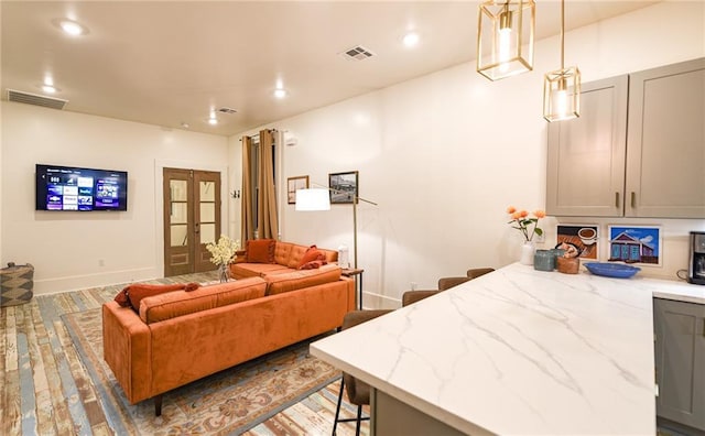 623-25 Louisa St, New Orleans, LA 70117 - kitchen with gray cabinets, open floor plan, wood finished floors, a kitchen breakfast bar, and light stone countertops