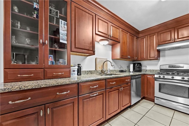603 E Manley Ave, Metairie, LA 70001 - kitchen with appliances with stainless steel finishes, under cabinet range hood, light tile patterned flooring, light stone counters, and brown cabinetry