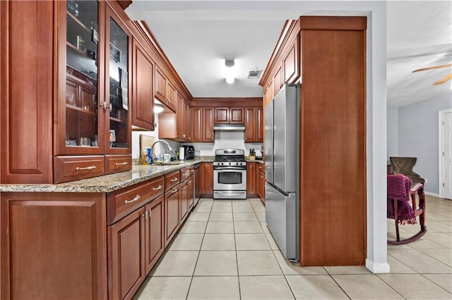 603 E Manley Ave, Metairie, LA 70001 - kitchen featuring appliances with stainless steel finishes, light tile patterned floors, light stone countertops, and glass insert cabinets