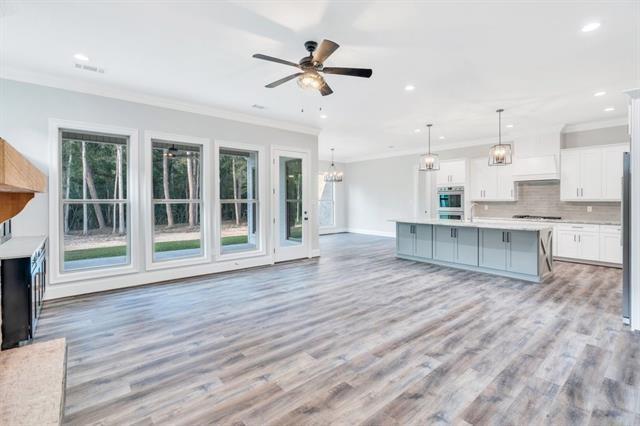 5053 Twin River Pl, Covington, LA 70433 - kitchen featuring ornamental molding, light countertops, healthy amount of natural light, white cabinets, and decorative backsplash