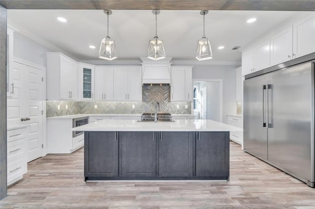 5028 Twin River Pl, Covington, LA 70433 - kitchen with built in refrigerator, white cabinets, light countertops, crown molding, and tasteful backsplash