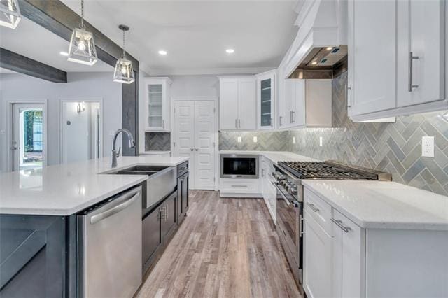 5028 Twin River Pl, Covington, LA 70433 - kitchen featuring appliances with stainless steel finishes, custom exhaust hood, light countertops, decorative backsplash, and recessed lighting