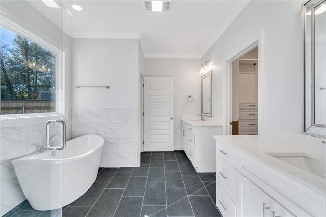 5028 Twin River Pl, Covington, LA 70433 - bathroom featuring two vanities, a freestanding bath, tile walls, tile patterned floors, and ornamental molding
