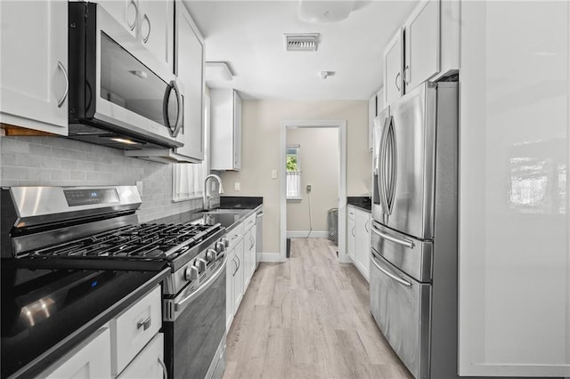 59246 Cypress Bayou Ln, Lacombe, LA 70445 - kitchen with appliances with stainless steel finishes, dark countertops, light wood-style floors, and backsplash