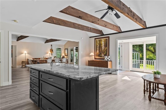 59246 Cypress Bayou Ln, Lacombe, LA 70445 - kitchen with open floor plan, dark cabinets, a center island, light stone counters, and light wood-type flooring