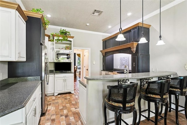 8 Oak Tree Dr, Slidell, LA 70458 - kitchen with a peninsula, brick flooring, white cabinets, ornamental molding, and a breakfast bar area