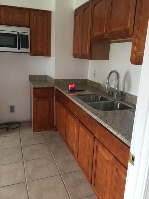 520 Emile Ave, Westwego, LA 70094 - kitchen featuring stainless steel microwave, brown cabinetry, and light tile patterned floors