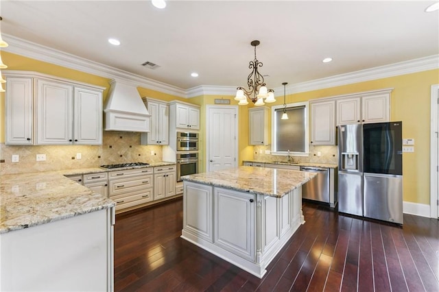 230 26th St, New Orleans, LA 70124 - kitchen with appliances with stainless steel finishes, custom range hood, a chandelier, light stone counters, and a kitchen island