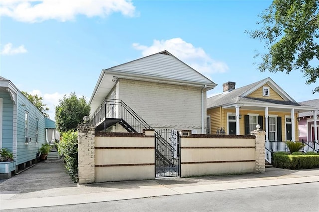 257 Cherokee St Unit 3, New Orleans, LA 70118 - view of front of house featuring a gate, a fenced front yard, covered porch, stairway, and brick siding