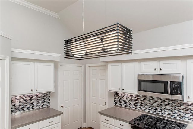 2212 Prairie Ct, Mandeville, LA 70448 - kitchen featuring stainless steel microwave, range, backsplash, white cabinetry, and ornamental molding