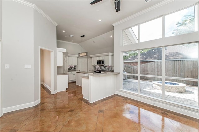 2212 Prairie Ct, Mandeville, LA 70448 - kitchen featuring stainless steel microwave, a peninsula, backsplash, ceiling fan, and white cabinetry