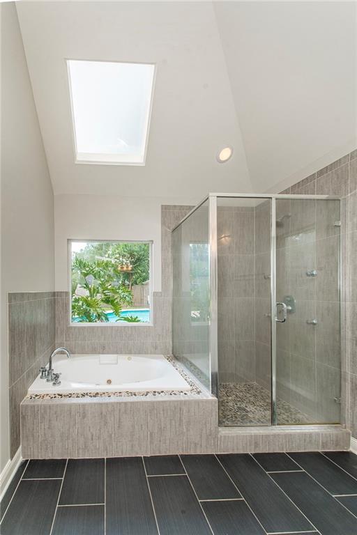 2212 Prairie Ct, Mandeville, LA 70448 - full bath with vaulted ceiling, a tub with jets, a skylight, a stall shower, and recessed lighting