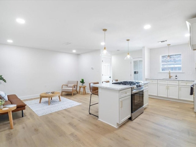 1340 Nursery Pl, Metairie, LA 70005 - kitchen with gas stove, light wood-style floors, white cabinets, recessed lighting, and hanging light fixtures