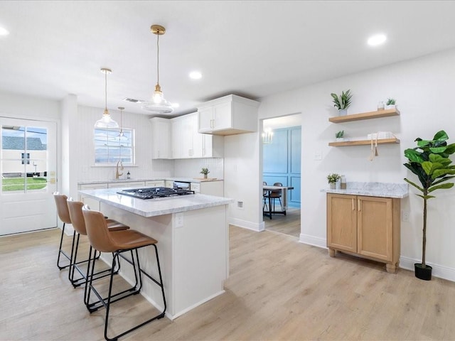 1340 Nursery Pl, Metairie, LA 70005 - kitchen featuring stainless steel gas cooktop, light wood-style floors, a center island, a kitchen breakfast bar, and recessed lighting