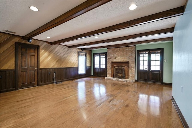 3541 Alan St, Metairie, LA 70002 - unfurnished living room featuring wooden walls, healthy amount of natural light, a brick fireplace, light wood-type flooring, and a textured ceiling