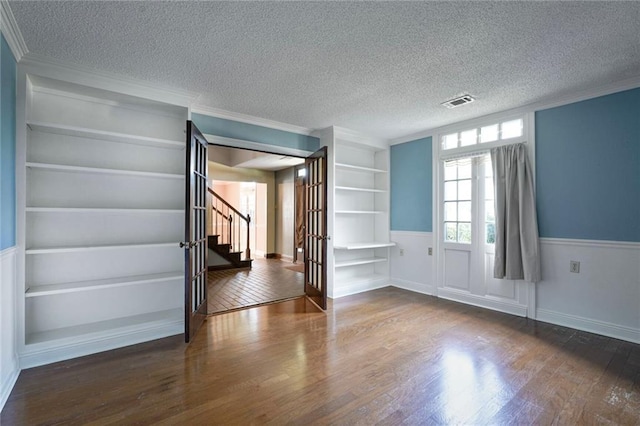 3541 Alan St, Metairie, LA 70002 - empty room featuring built in features, a textured ceiling, wood finished floors, ornamental molding, and stairway