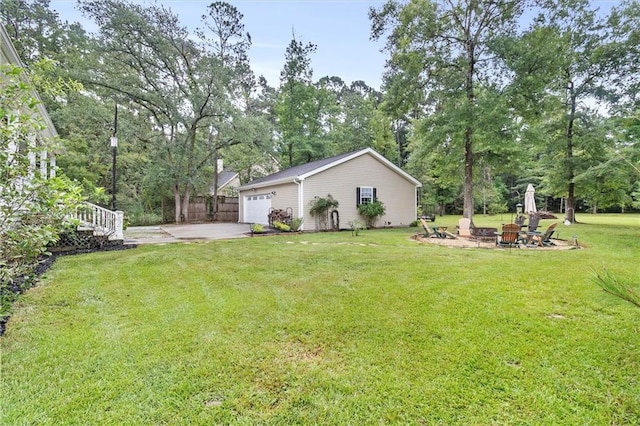 28 Hyacinth Dr, Covington, LA 70433 - view of green lawn featuring a fire pit, a garage, view of wooded area, and driveway