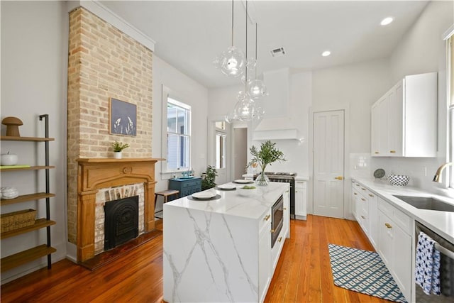 3311 Saint Ann St, New Orleans, LA 70119 - kitchen with a kitchen island, stainless steel appliances, white cabinetry, light stone counters, and light wood finished floors