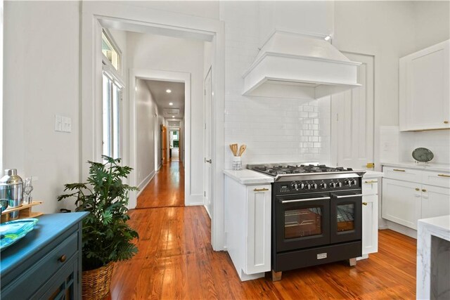 3311 Saint Ann St, New Orleans, LA 70119 - kitchen with double oven range, tasteful backsplash, white cabinets, and wood finished floors