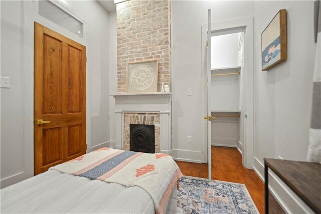 3311 Saint Ann St, New Orleans, LA 70119 - bedroom featuring wood finished floors, a spacious closet, and a brick fireplace