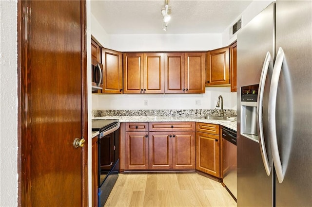 2305 Cleary Ave Unit 214, Metairie, LA 70001 - kitchen with stainless steel appliances, light wood-type flooring, light stone countertops, track lighting, and brown cabinetry