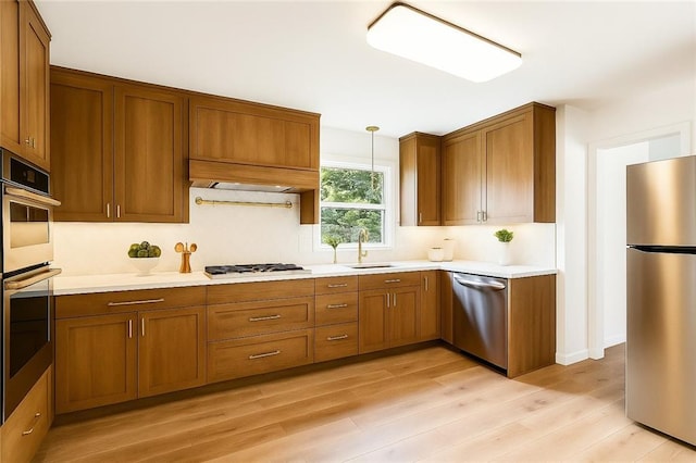6213 Rosalie Ct, Metairie, LA 70003 - kitchen featuring stainless steel appliances, brown cabinets, light countertops, and light wood-type flooring