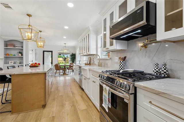 4721 Chastant St, Metairie, LA 70006 - kitchen featuring stainless steel appliances, a chandelier, a kitchen island, light stone counters, and a breakfast bar