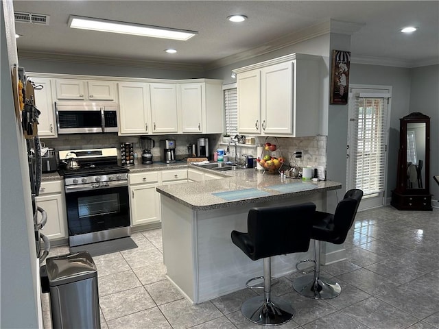 532 Deerfield Rd, Terrytown, LA 70056 - kitchen with appliances with stainless steel finishes, a peninsula, decorative backsplash, white cabinets, and ornamental molding
