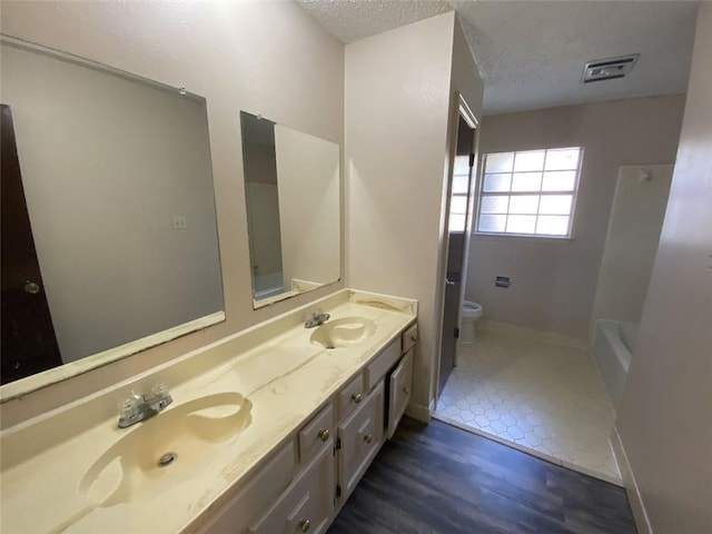 1411 Patriot St, Slidell, LA 70458 - bathroom featuring double vanity, a textured ceiling, wood finished floors, and washtub / shower combination