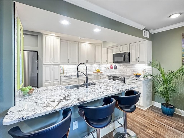 60 Chamale Cv Unit 60, Slidell, LA 70460 - kitchen with stainless steel appliances, crown molding, a kitchen breakfast bar, light stone countertops, and tasteful backsplash