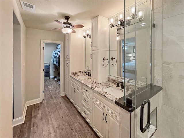 60 Chamale Cv Unit 60, Slidell, LA 70460 - bathroom featuring wood finished floors, double vanity, a ceiling fan, a spacious closet, and a textured ceiling