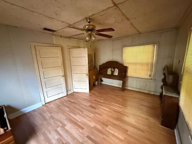 5013 Douglas Ave, Baton Rouge, LA 70805 - unfurnished bedroom with light wood-style flooring, a ceiling fan, and wooden walls
