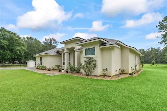 22484 Treadaway St, Mandeville, LA 70471 - view of side of home with a storage unit, a yard, stucco siding, roof with shingles, and a garage