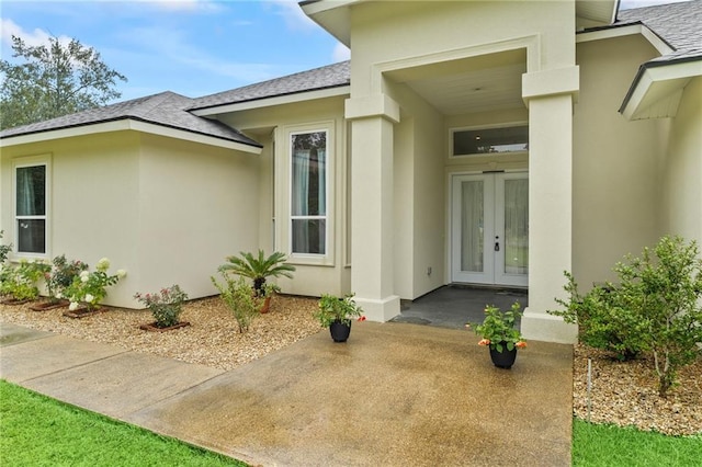 22484 Treadaway St, Mandeville, LA 70471 - view of exterior entry featuring french doors, a shingled roof, and stucco siding