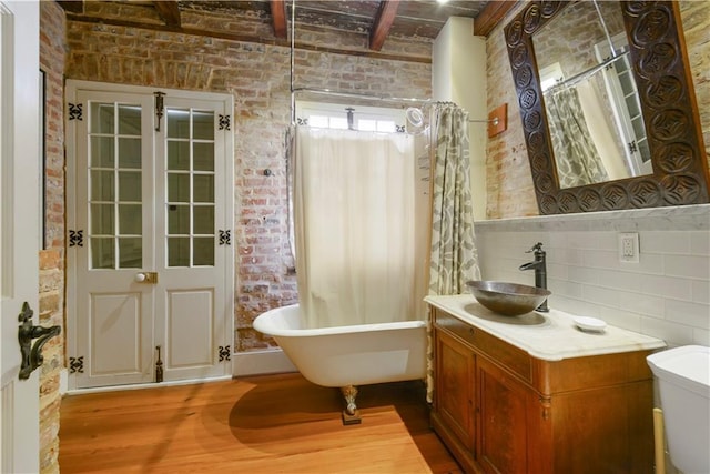 101921 Saint Peter St, New Orleans, LA 70116 - bathroom featuring wood finished floors, a soaking tub, vanity, beam ceiling, and brick wall