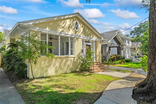 1316 Lowerline St, New Orleans, LA 70118 - view of front of house with brick siding, a ceiling fan, and a front lawn