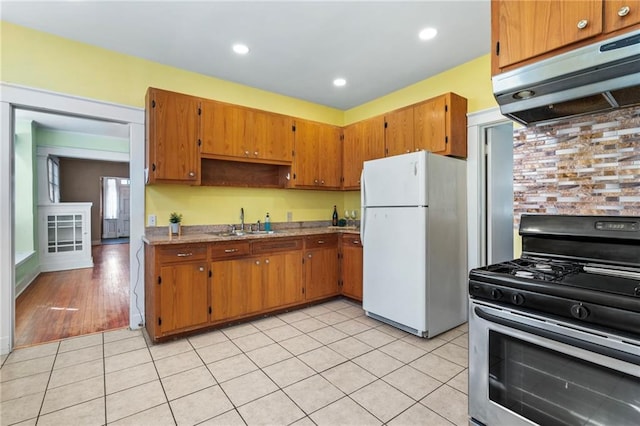 1316 Lowerline St, New Orleans, LA 70118 - kitchen featuring freestanding refrigerator, gas range, under cabinet range hood, brown cabinetry, and recessed lighting