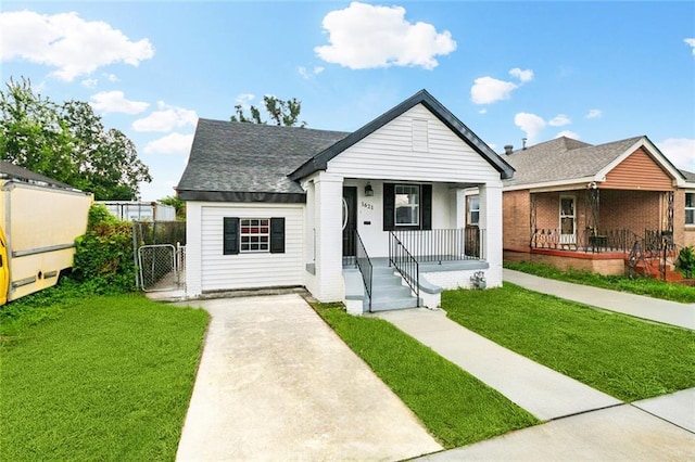 1621 Congress St, New Orleans, LA 70117 - view of front of home with covered porch, a front lawn, a gate, and a shingled roof