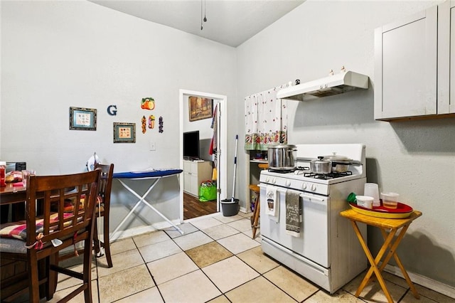 264951 Bruxelles St, New Orleans, LA 70119 - kitchen featuring white gas range, under cabinet range hood, light tile patterned floors, and white cabinetry