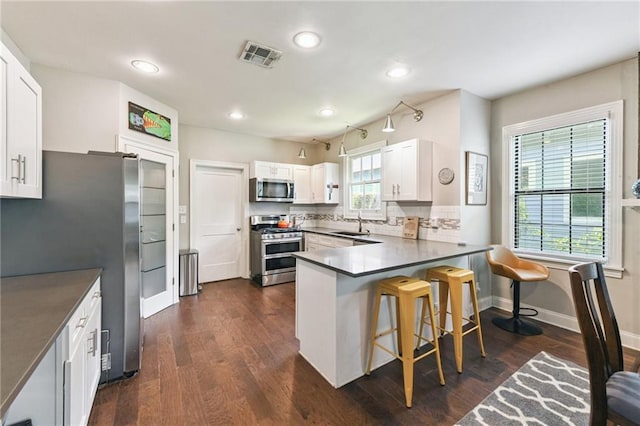 4472 Demontluzin St, New Orleans, LA 70122 - kitchen with stainless steel appliances, recessed lighting, a peninsula, a kitchen bar, and white cabinetry