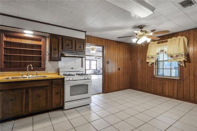 15 Tulip Dr, Gretna, LA 70053 - kitchen with white gas range, under cabinet range hood, wood walls, light countertops, and dark brown cabinets