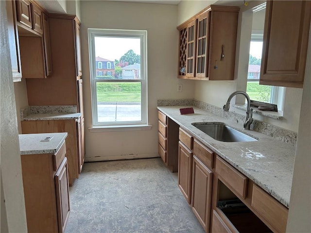 4317 James Dr, Metairie, LA 70003 - kitchen with light stone countertops, glass insert cabinets, and brown cabinetry
