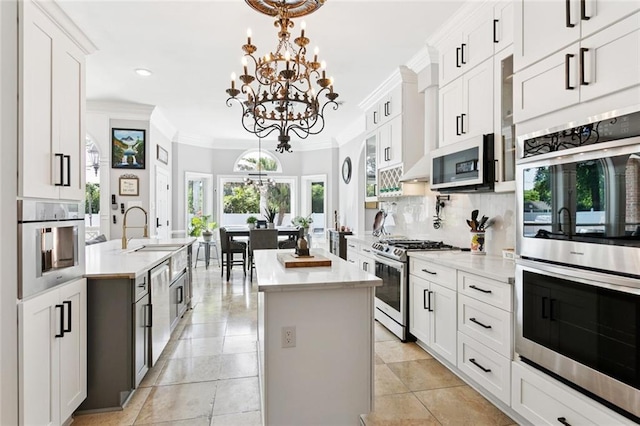 299 Sarah Victoria Dr, Belle Chasse, LA 70037 - kitchen featuring stainless steel appliances, a kitchen island, ornamental molding, backsplash, and a chandelier
