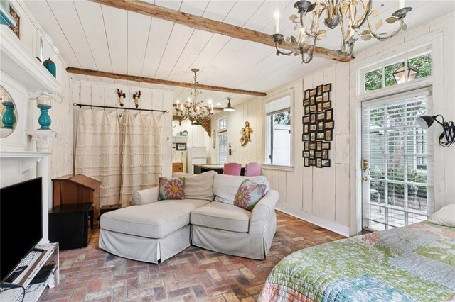 718 Ursulines Ave Unit D, New Orleans, LA 70116 - bedroom featuring a chandelier, access to outside, multiple windows, wood walls, and brick flooring