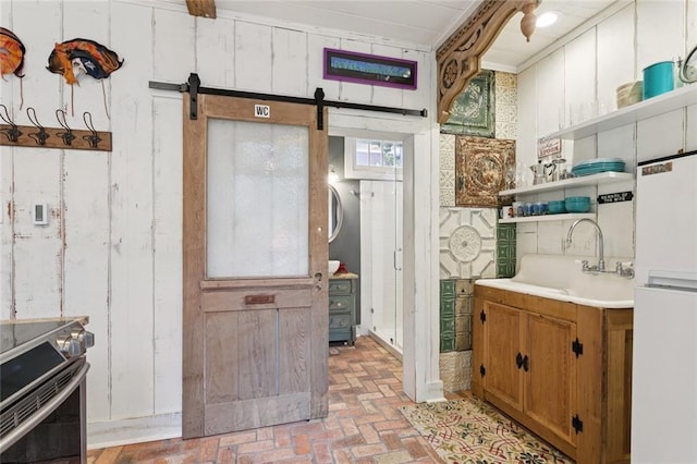 718 Ursulines Ave Unit D, New Orleans, LA 70116 - kitchen with stainless steel range with electric stovetop, brick floors, open shelves, a barn door, and brown cabinets