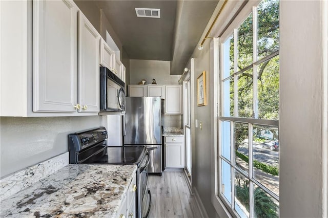 2512 Magazine St Unit D, New Orleans, LA 70130 - kitchen with stainless steel appliances, white cabinets, light wood-style floors, and light stone counters